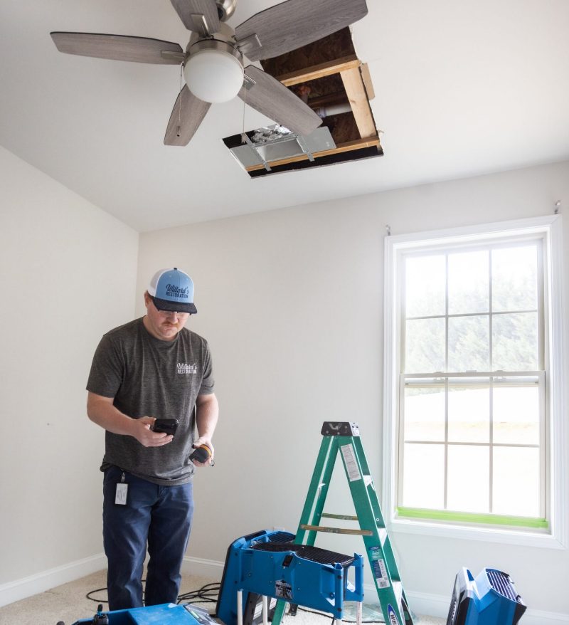 A technician opening a ceiling to trace water damage