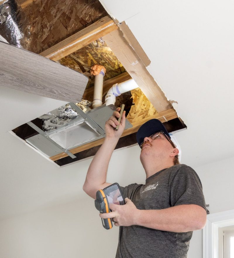 A technician taking a moisture reading in a ceiling cavity