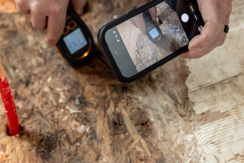 A moisture reading being documented and photographed for the job file